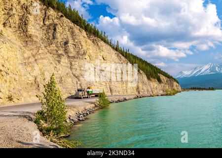 Traktoranhänger fährt auf dem Alaska Highway entlang des Muncho Lake, umgeben von den kanadischen Rocky Mountains, British Columbia und Kanada Stockfoto