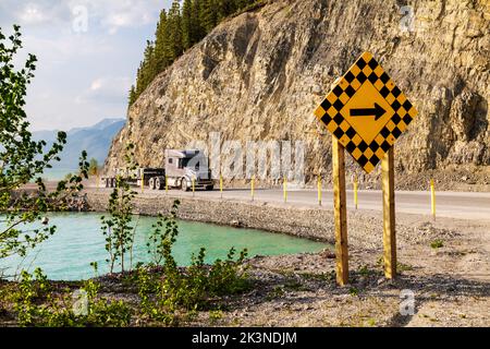 Traktoranhänger fährt auf dem Alaska Highway entlang des Muncho Lake, umgeben von den kanadischen Rocky Mountains, British Columbia und Kanada Stockfoto
