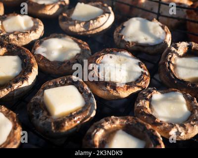 Mit Käse gefüllte Pilze. Gegrillte Champignons gefüllt mit Käse, selektiver Fokus. Heiße portobello-Tassen mit geschmolzenem Mozzarella auf dem Grillrost Stockfoto