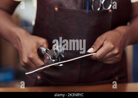 Nahaufnahme von weiblichen handwerklichen Stanzlöchern in handgefertigtem Gürtel in Lederwerkstatt, Kopierraum Stockfoto