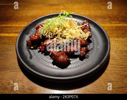 Gebackenes Rindfleisch mit Gemüse auf dem schwarzen Teller bereit zum Essen Stockfoto