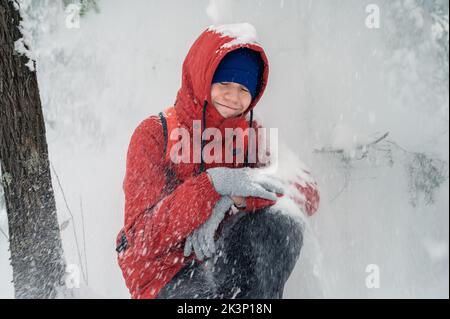 Porträt eines Jungen im Teenageralter, der im Winter im Wald schneit und spaßig ist Stockfoto