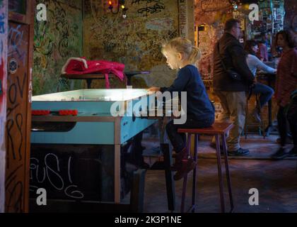 Ein junges Mädchen, das an einem Tisch in der Szimplakert Ruin Bar sitzt Stockfoto