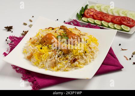 Dhum biriyani mit Jeera-Reis und Gewürzen in Erdenware mit Salat auf weißem Hintergrund. Stockfoto