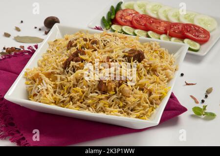 Dhum biriyani mit Jeera-Reis und Gewürzen in Erdenware mit Salat auf weißem Hintergrund. Stockfoto