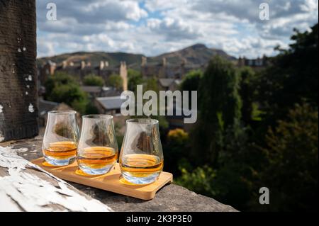 Flug von Single Malt Scotch Whisky serviert auf alten Fensterbank im Scottisch House mit Blick auf den alten Teil der Stadt Edinburgh und Hügel, Schottland, Großbritannien, DRAM Stockfoto