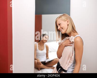 Es ist ihr glücklicher Ort, andere Kleider anzuprobieren. Zwei Freunde wählen Outfits aus ihrer Garderobe. Stockfoto