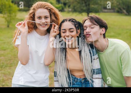 Eine Gruppe von multiethnischen Teenagers posiert mit lustigen Gesichtsausdrücken im Freien und lächelt aufrichtig vor der Kamera. Outdoor-Lifestyle. Jugendstil Stockfoto