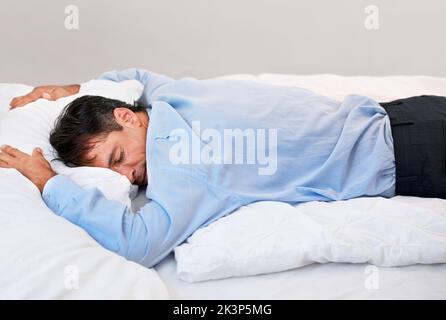 Erschöpft. Ein Geschäftsmann lag völlig erschöpft auf seinem Bett. Stockfoto