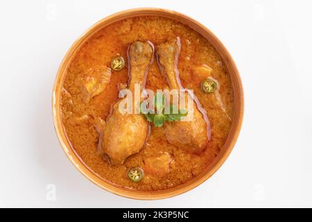 Chicken-Kerrys oder Masala, deshi-Stil Chicken-Kerrys mit gebratener Kokosnuss auf traditionelle Weise und in einem schwarzen Keramikgefäß angeordnet, das auf ein g gelegt wird Stockfoto