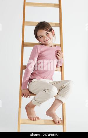 Shes a cutie. Studio-Portrait eines niedlichen kleinen Mädchens, das auf einer Leiter sitzt. Stockfoto