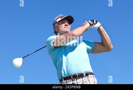 Eine gute Fahrt bewundernd. Ein reifer Mann, der einen Golfschuss auf dem Golfplatz spielt. Stockfoto