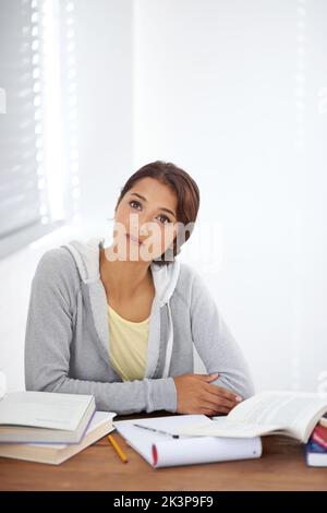 Eine schöne Studentin, die versucht, einen Studienblock in ihrem Schlafsaal zu überwinden. Stockfoto