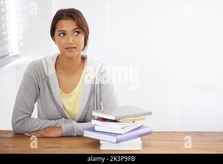 Ich sollte anfangen. Kopf- und Schulteraufnahme einer jungen Frau, die an ihrem Schreibtisch sitzt und denkt. Stockfoto