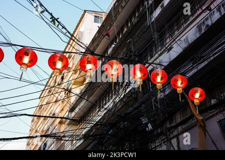 Bangkok, Thailand - 23. Januar 2022: Während der chinesischen Neujahrswoche hängen die roten Globenlaternen mit chinesischer Sprache das Glück am Draht über der Straße Stockfoto