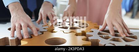 Geschäftsleute stellen Holzgeräte am Arbeitsplatz zusammen, arbeiten im Team Stockfoto