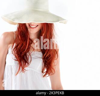 Schützt meinen zarten Teint. Eine wunderschöne junge rothaarige Frau, die einen Sonnenhut trägt. Stockfoto