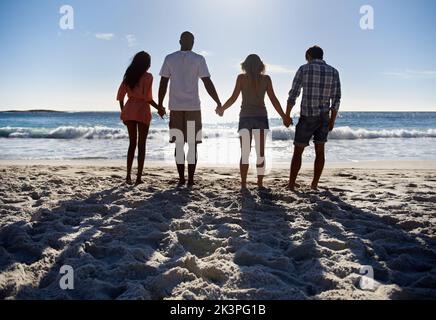 Genießen Sie die Aussicht. Zwei junge Paare blicken auf den Strand. Stockfoto