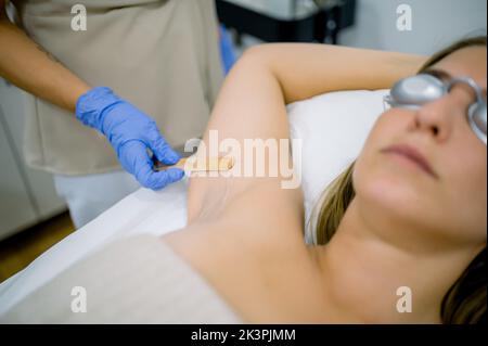 Crop Kosmetikerin Anwendung Kühlgel auf Client Stockfoto