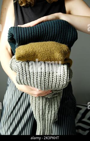 Frau hält in ihrem Handstapel warme Wollpullover und Strickjacken Stockfoto