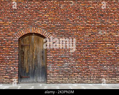 Rote Backsteinmauer mit gewölbter Holztür Stockfoto