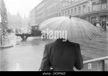 Schirme in der 1950s. Der Regen ergießt und eine Frau wird gesehen, wie sie einen Regenschirm über sich hält. Es ist ein regnerischer Tag in Stockholm Schweden 1953. ref 2A-1 Stockfoto