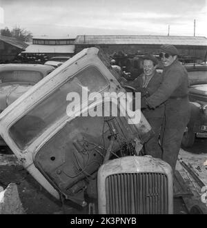 In der 1940s. Arbeiter auf einem Schrottplatz nehmen ein Auto mit Gewalt auseinander. Das während des Zweiten Weltkriegs aufgenommene Bild und das Recycling waren wichtig, um das Material in den Industrien wiederzuverwenden, die die schwedische Armee mit Waffen und Fahrzeugen versorgten. Schweden 1942. Kristoffersson Ref. AF18-2 Stockfoto