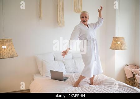 Fröhliche blonde Dame mit Spaß im Schlafzimmer Stockfoto
