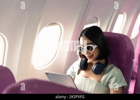 Passagier mit Tablet-Computer in der Flugzeugkabine während des Fluges. Stockfoto