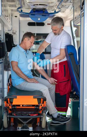 Kranker erwachsener Mann, der medizinische Notversorgung erhält Stockfoto