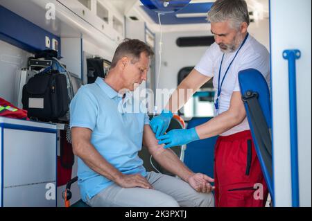 Kranke männliche Person, die medizinische Notfallversorgung erhält Stockfoto