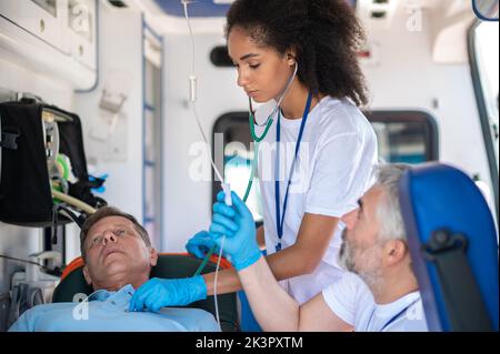 Paramedizinisches Personal, das einen kranken Mann medizinisch versorgt Stockfoto