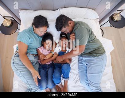 Familienbett, zu Hause entspannen und Eltern im Schlafzimmer mit Kindern, Pflege für Comic-Kinder und Liebe im Haus zusammen von oben. Draufsicht auf Mädchen Geschwister Stockfoto