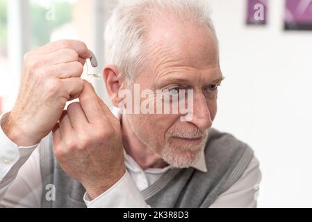 Älterer Mann, der Hörgeräte stellt Stockfoto