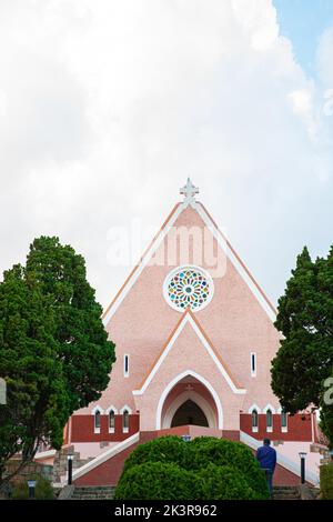 Mai Anh Domaine De Marie Kirche Diözese auf blauem Himmel Hintergrund, versteckt hinter Kiefern am sonnigen Tag mit Vorderansicht, in Da Lat, Lam Dong prov Stockfoto