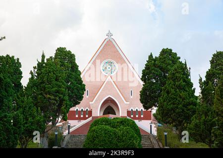 Kacheldach der Kirche und Kruzifix Kreuz isoliert auf blauem Himmel Hintergrund in Da Lat, Lam Dong, Vietnam Stockfoto