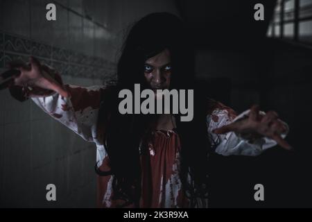 Grusel Zombies Geisterspaziergang. Asiatische weibliche Make-up Zombie, Frau Geist Horror gruselig beängstigend haben Haare Gesicht mit Blut gehen nach Kamera an einem Stockfoto