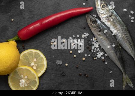 Frischer, roher Fisch mit Zitrone und Chili auf Schieferplatte Stockfoto