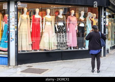 Shopper beim Blick auf das Fenster eines indianischen asiatischen Damenmode- und Sari-Shops in Southall High Street, Southall, West London, England, Großbritannien Stockfoto