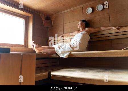 Ältere Frau sitzt entspannt in eine Holzsauna Stockfoto