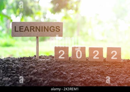 Jahr 2022 Life Lessons and Learnings Konzept. Holzblöcke im natürlichen Hintergrund bei Sonnenuntergang. Stockfoto