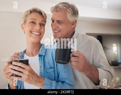 Kaffee, Liebe und altes Paar lächeln zu Hause und trinken Getränke, Koffein oder Cappuccino. Entspannen, Ruhestand und Tee mit älteren, glücklichen verheirateten Mann und Stockfoto