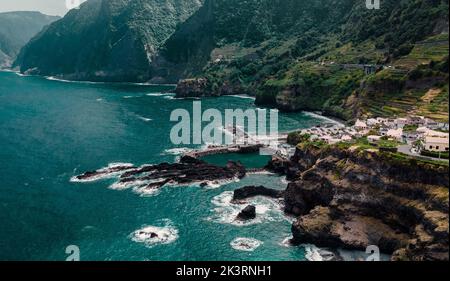 Natürliche Schwimmbäder und kleine Stadt auf Klippen, Atlantikküste. Madeira, Portugal. Luftdrohnenfotografie Stockfoto