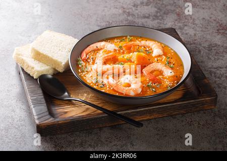 Gesunde Bio-Kürbiscremesuppe mit Garnelen, Sesam und Thymian in Nahaufnahme auf einem Holztablett auf dem Tisch. Horizontal Stockfoto