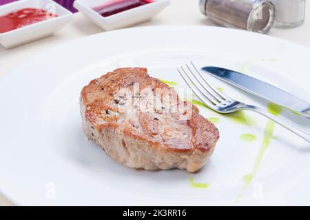 Leckeres saftiges Schweinesteak auf einem weißen Teller Stockfoto