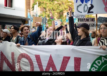 Jubelnde Teilnehmer*innen hinter Banner 'Klimagerechtigkeit jetzt!'. Am 23.9.2022 sammeln sich in München bis zu 10,000 Menschen, um gemeinsam mit Fridays for future auf dem globalen Klimabereich für Klimagerechtigkeit, den Ausbau der dezentralen erneuerbaren Energien, kostengünstigen ÖPNV und für ein 100 Mrd. Euro Sondervermögen für gerechte Klimaschutzmaßnahmen und Krisenprävention zu demontieren. Das Motto des Großstreiks war wieder People Not Profit. -- jubelnde Teilnehmer hinter dem Banner "Climate Justice Now! Am 23. September 2022 versammelten sich bis zu 10.000 Personen in München Stockfoto