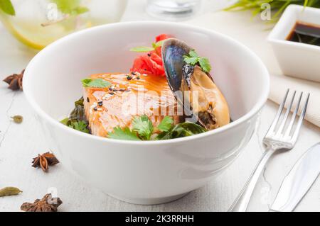 Leckeres Lachssteak mit Meeresfrüchten und Muscheln in einer weißen Schüssel Stockfoto