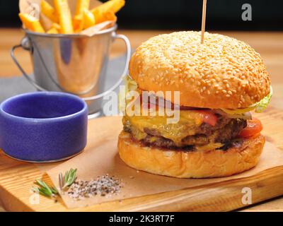 Leckere Burger mit zwei saftigen Rinderpasteten und Käse, mit Pommes frites Stockfoto