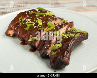 Leckere Schweinekirschrippen mit Grillsauce, grünen Zwiebeln und Sesam Stockfoto