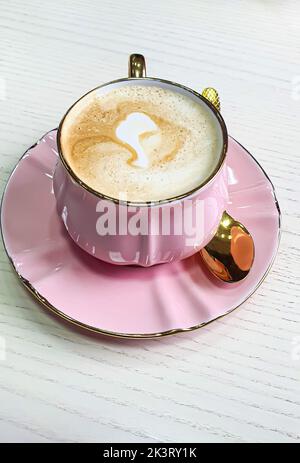 Cappuccino mit Schaum in einer rosa Tasse auf einem hellen Tisch. In Kaffee ruhen. Platz kopieren Stockfoto